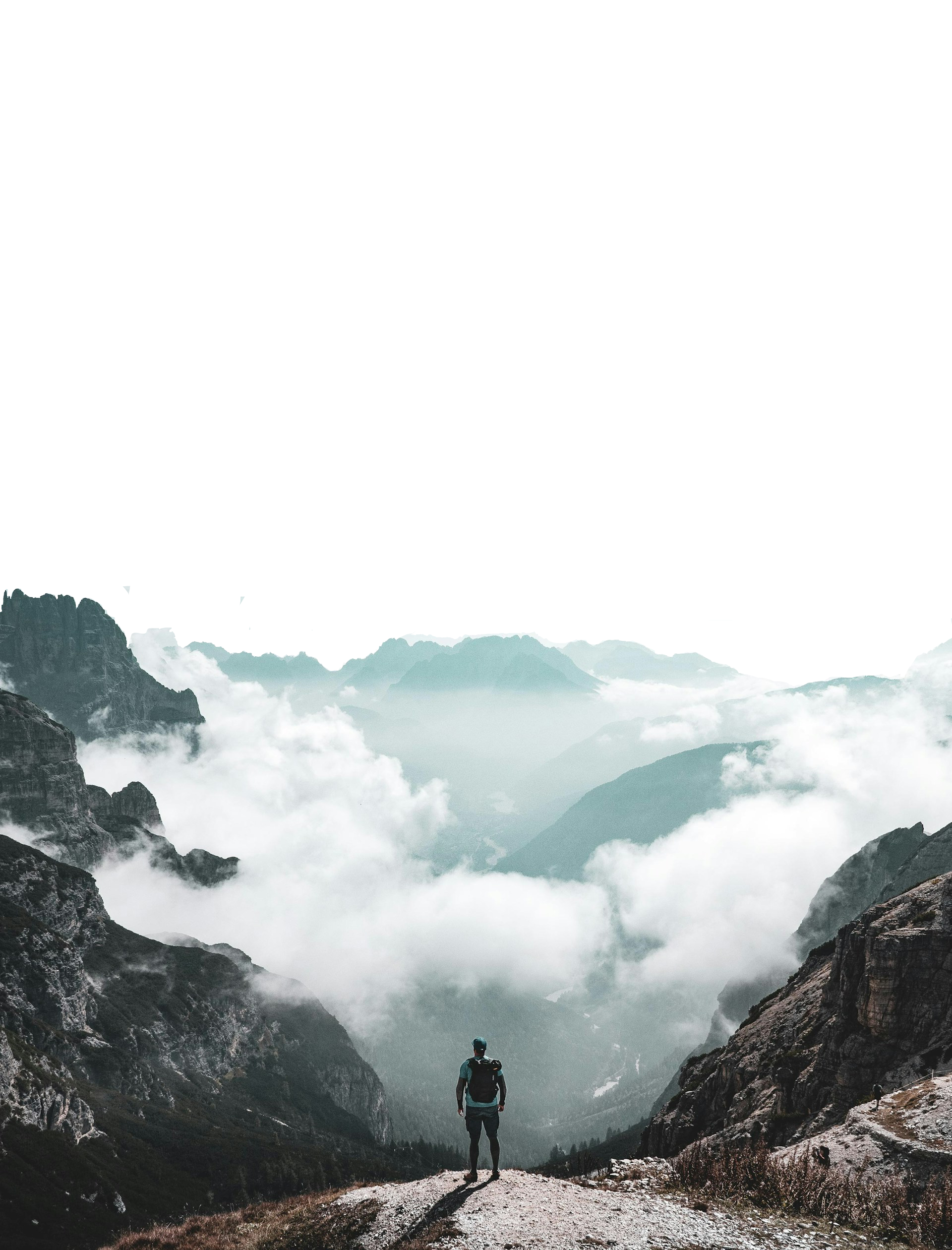 Person standing on mountain ledge overlooking misty valley