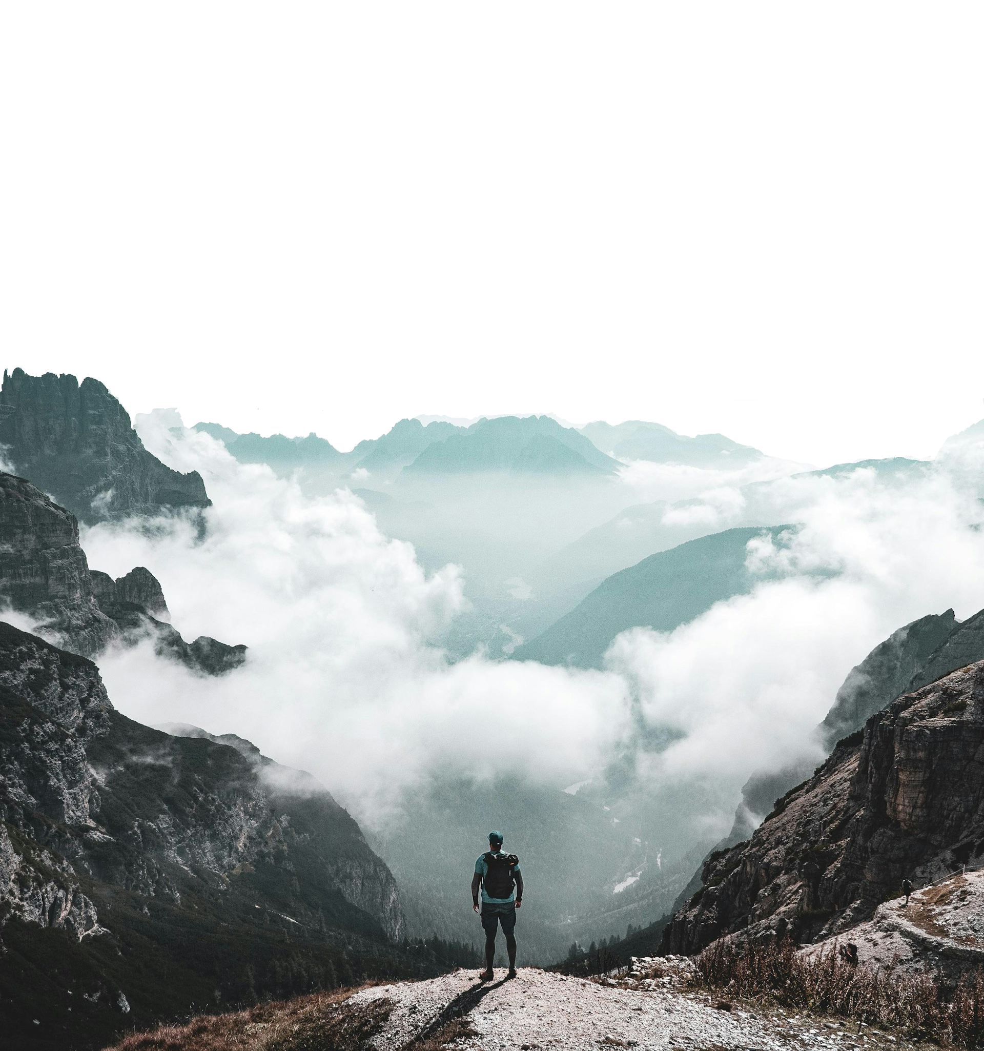 Person standing on mountain peak overlooking misty valleys